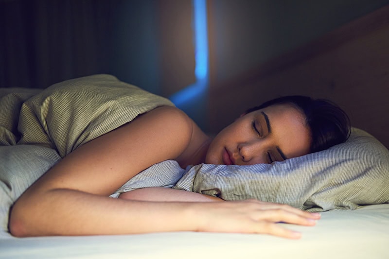 a young woman sound asleep in her bedroom.