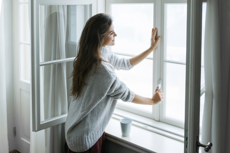 What Is an Air Handler? Photo of a woman opening a window in her home.
